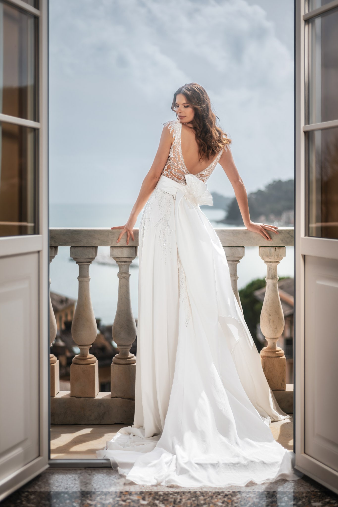 Sposa in abito bianco su balcone panoramico vista mare.