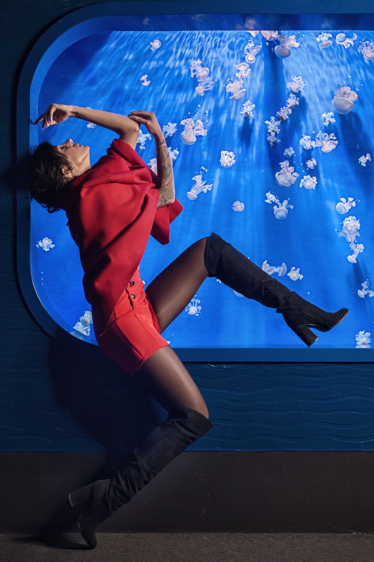 Ritratto creativo di donna in rosso davanti a un acquario blu