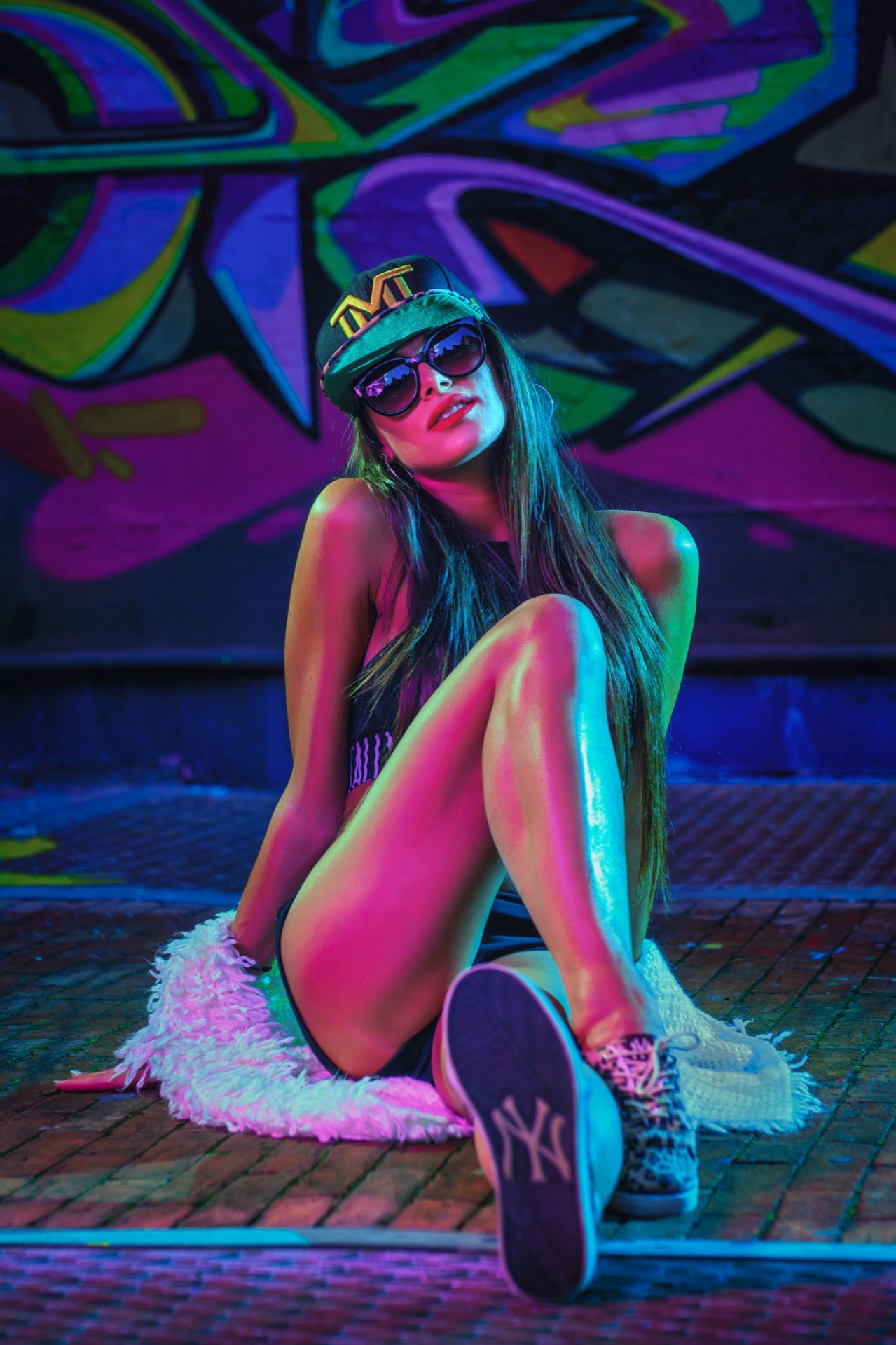 Ritratto creativo di donna con cappellino e occhiali tra luci neon